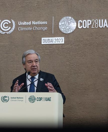 A man standing at a podium in front of flags.
