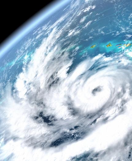 Satellite view of a swirling hurricane over the ocean with a visible coastline in the top right, showcasing the storm's spiral cloud formation.